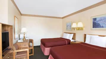 A hotel room with two beds, a desk with a chair, a television, and two wall-mounted lamps.