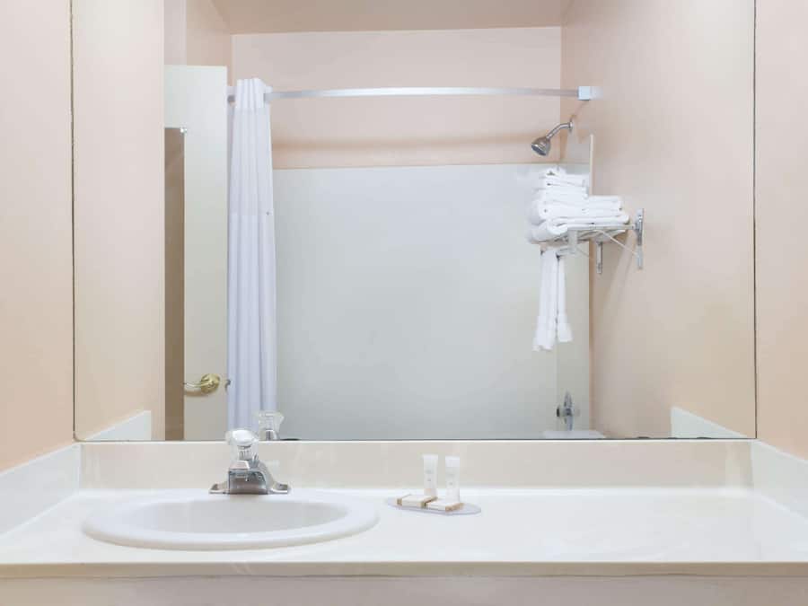 Un bagno con lavandino, specchio, doccia e porta asciugamani.