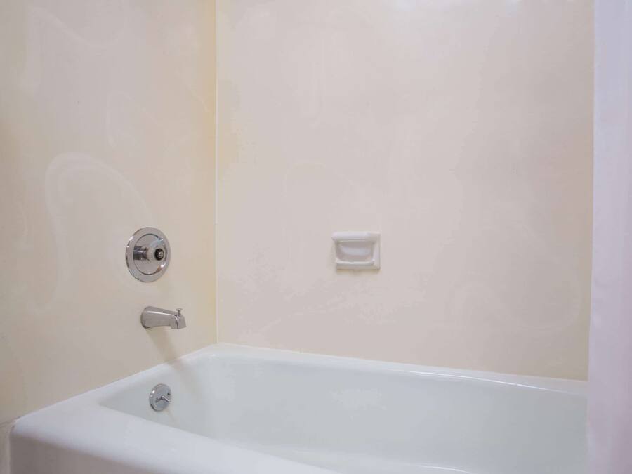 A white bathtub with a chrome faucet and a soap dish on the wall.