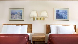 A hotel room with two beds, a nightstand, two wall-mounted lamps, and two framed landscape paintings. - Howard Johnson by Wyndham Brigham City (Brigham City)