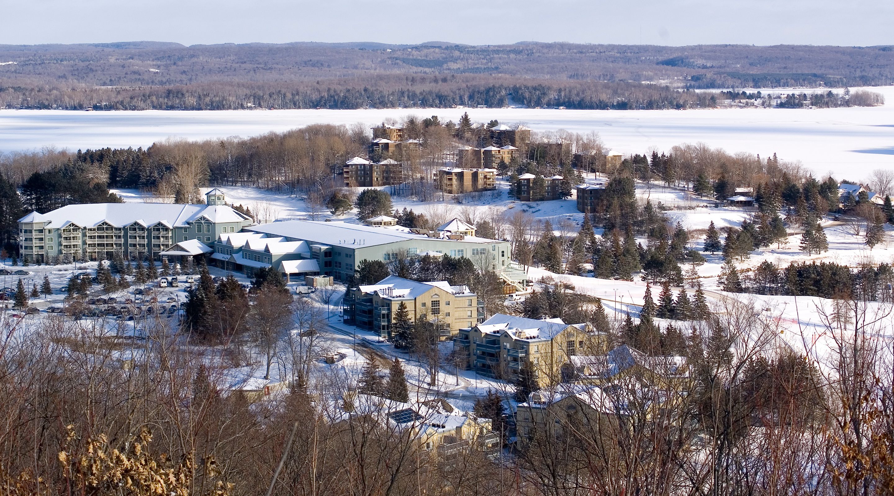 A snow-covered resort with multiple buildings, including a large hotel with a central courtyard and several smaller structures.