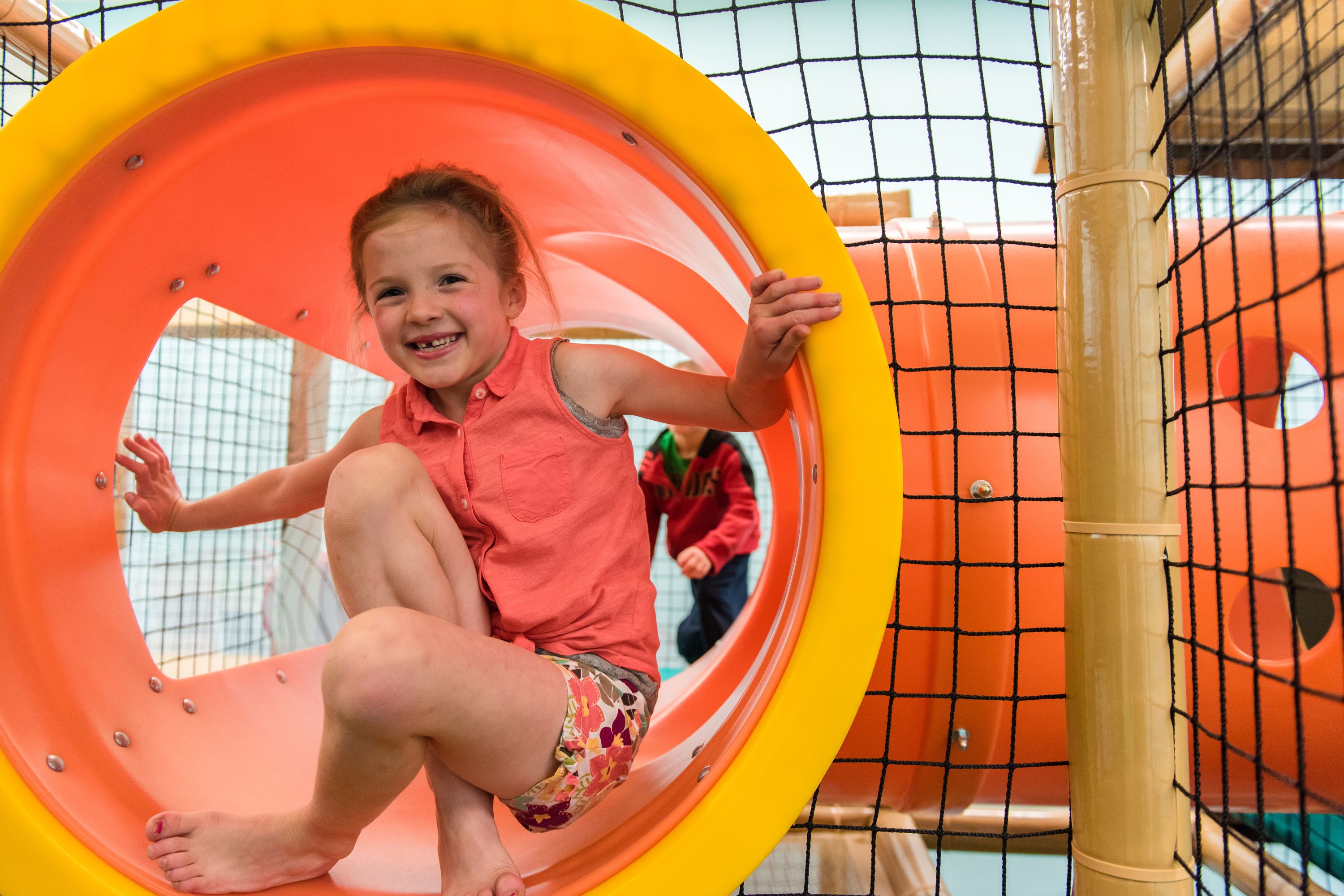 A child sliding down a brightly colored spiral slide in a playground.