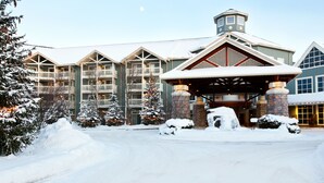 A large lodge with multiple balconies, a stone entrance, and snow-covered surroundings. - Deerhurst Resort (Huntsville)
