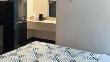 Une chambre d’hôtel avec un lit, une kitchenette et un tableau au mur.