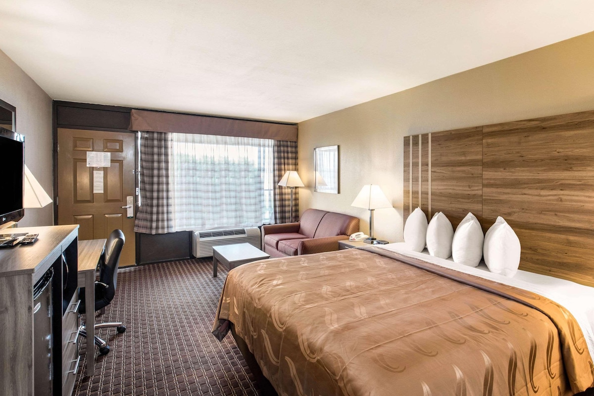 Habitación de hotel con cama, escritorio, silla y televisor.