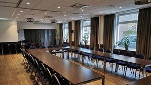 A conference room with long tables and chairs, large windows with curtains, and a projector screen. - Best Western Hotel Baars (Harderwijk)
