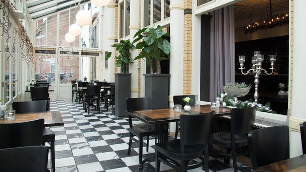 A restaurant with checkered flooring, black and white decor, and large windows. - Best Western Hotel Baars (Harderwijk)