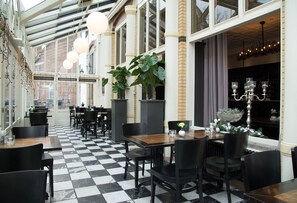 A restaurant with checkered flooring, black and white decor, and large windows. - Best Western Hotel Baars (Harderwijk)