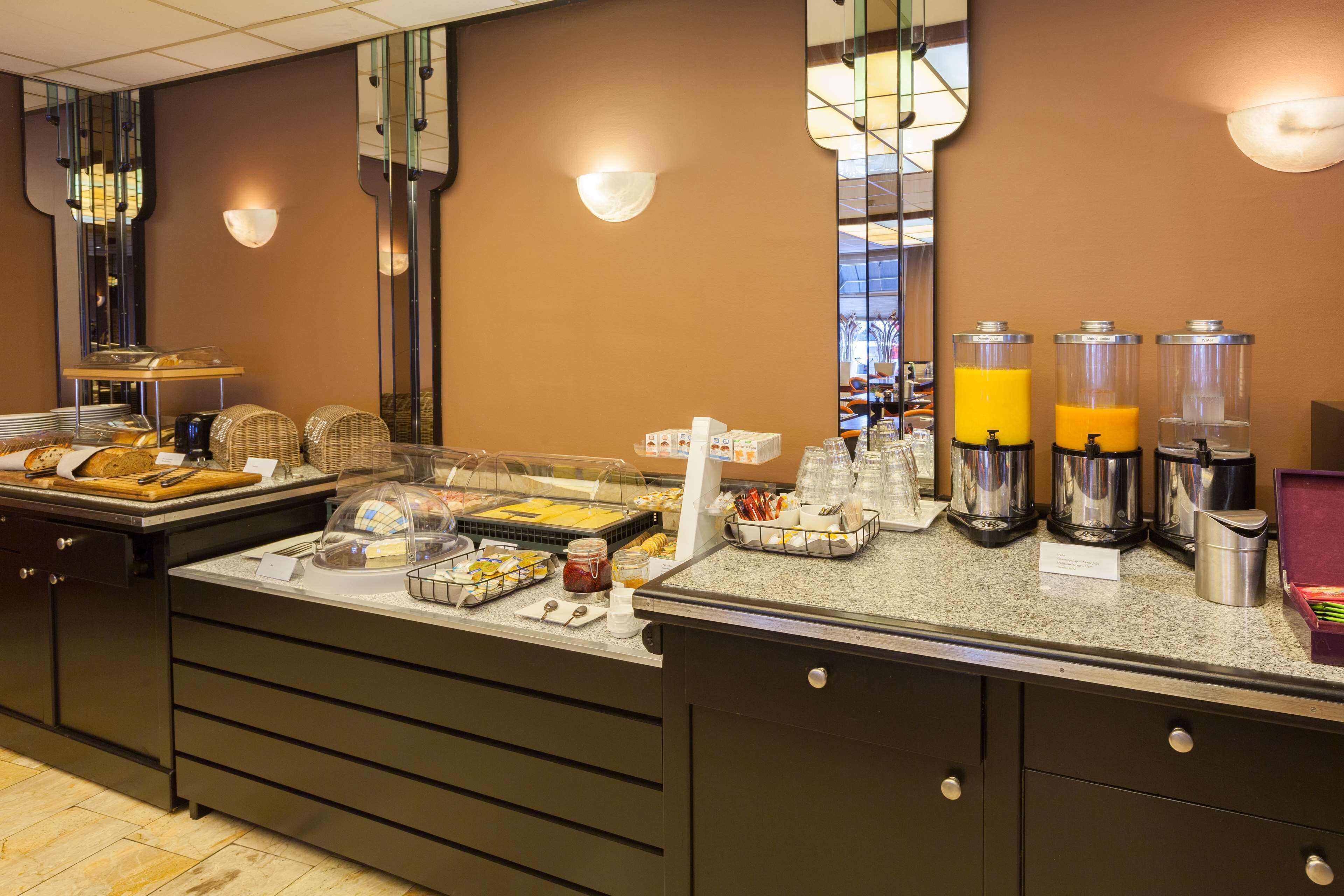 A buffet setup with various food items, a coffee station, and a juice dispenser.