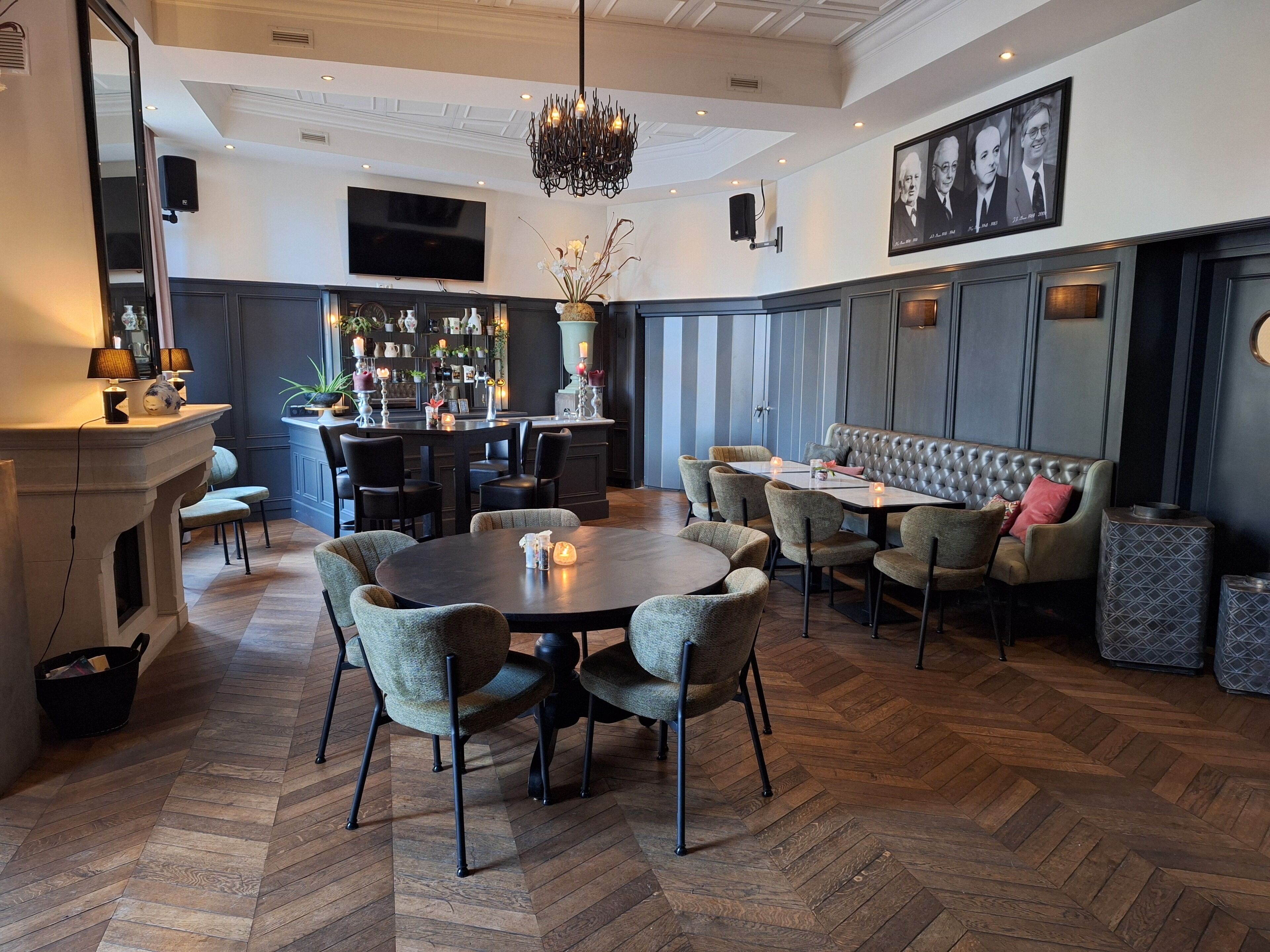Een moderne eetruimte met een ronde tafel, beklede stoelen, een bar met planken en een grote televisie.