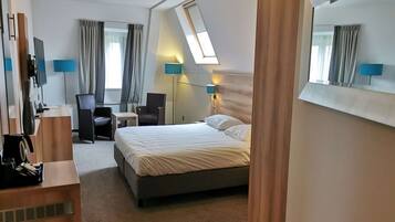 Ein Hotelzimmer mit Bett, Schreibtisch, Stuhl und einem großen Spiegel.