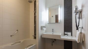 Een moderne badkamer met een bad, douche, wastafel en handdoekhouder.