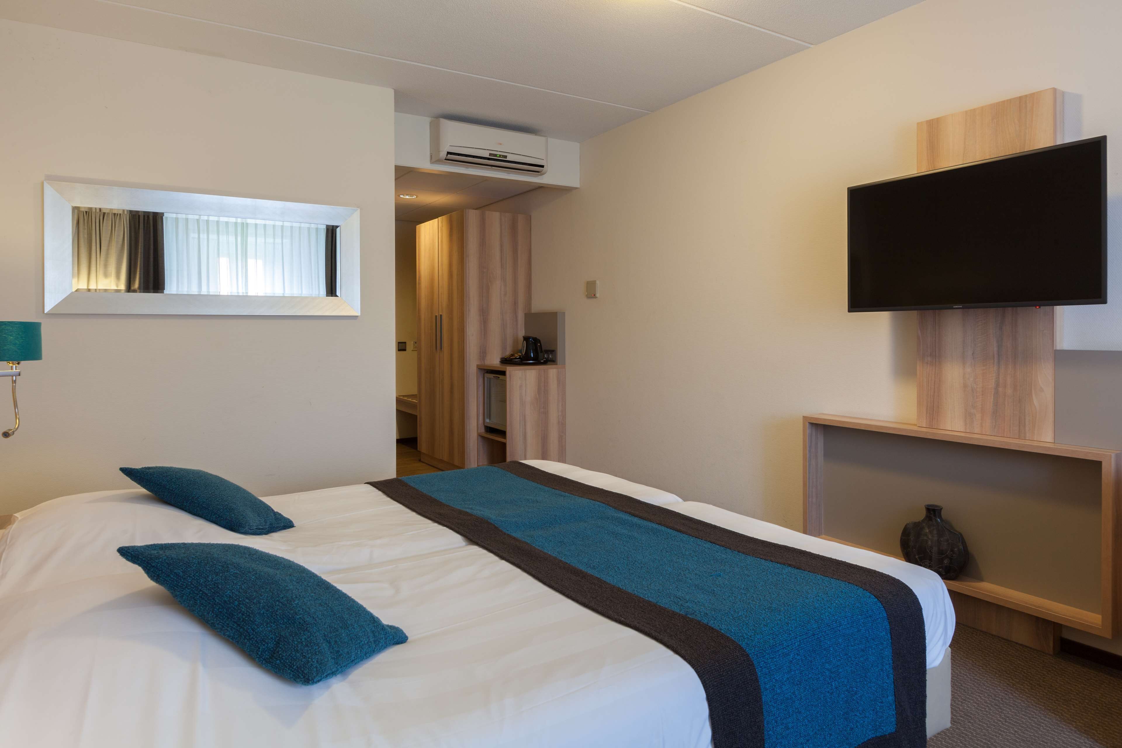 Une chambre d’hôtel avec un lit, une télévision et une fenêtre avec des rideaux.