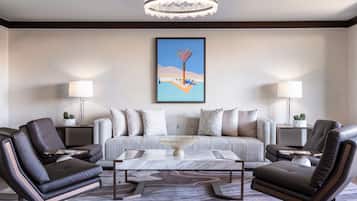 A modern living room with a sofa, two armchairs, a coffee table, and a chandelier.