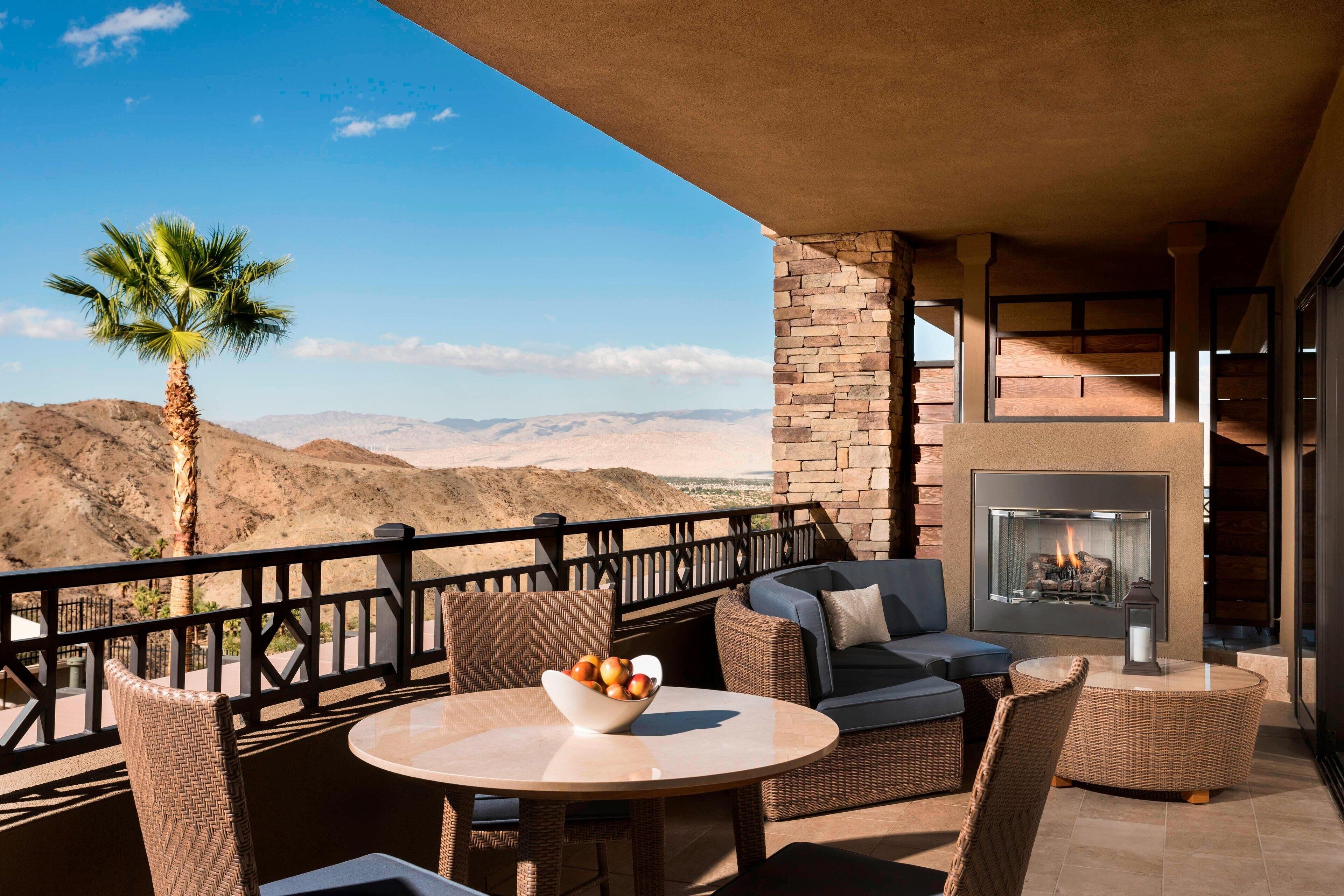 A balcony with wicker furniture, a bowl of fruit, and a fireplace.
