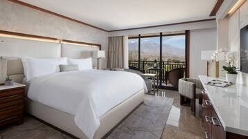 Ein geräumiges Hotelzimmer mit einem großen Bett, einem Schreibtisch und einem Balkon mit Bergblick.
