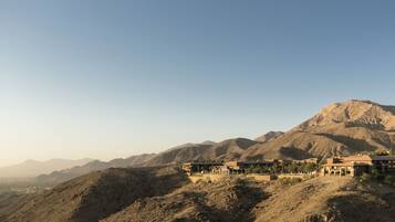 Un resort en el desierto con varias construcciones, incluyendo un edificio principal del resort y casas de huéspedes más pequeñas, con montañas al fondo.
