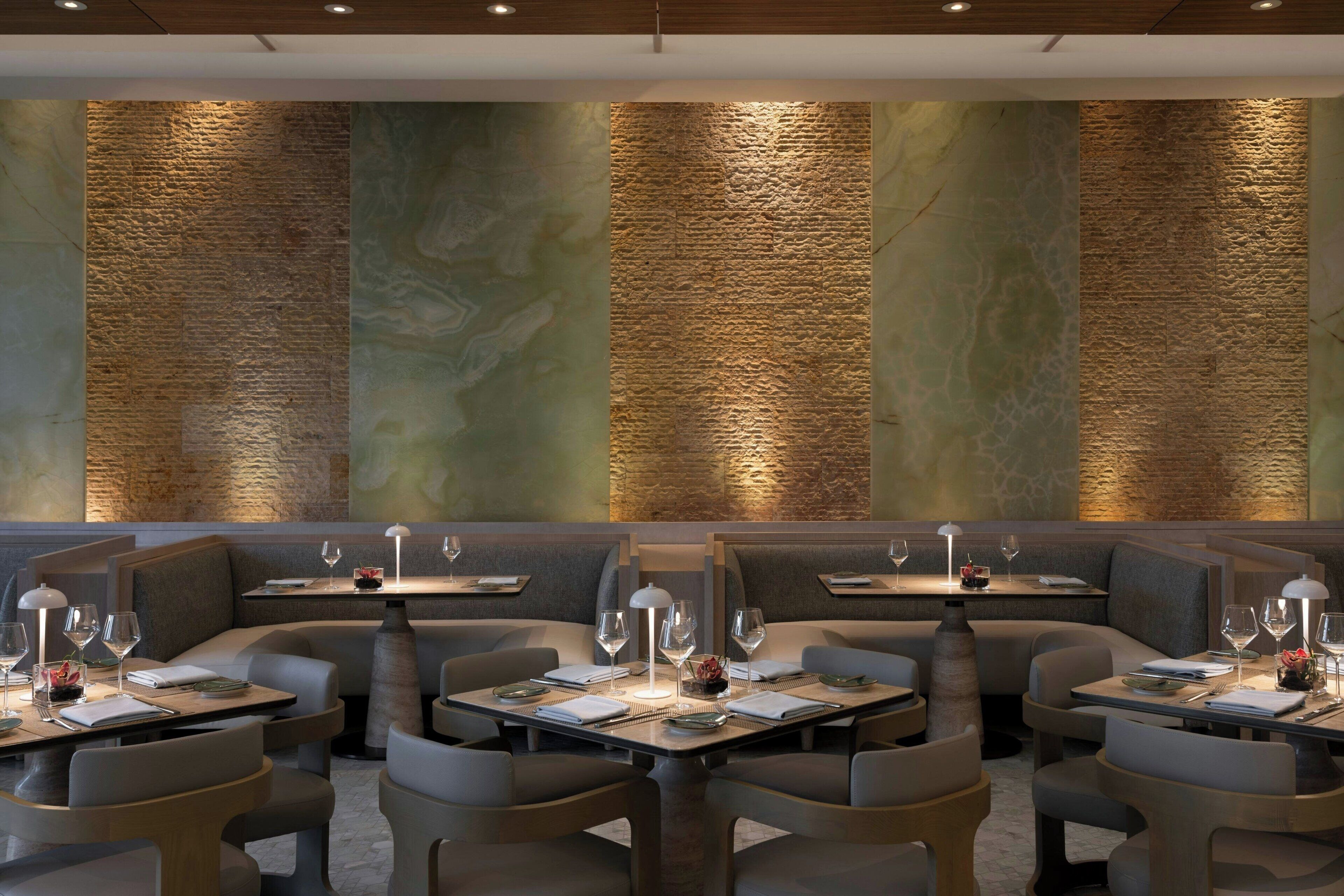 A restaurant with booths and tables, each with a lamp, wine glasses, and menus.