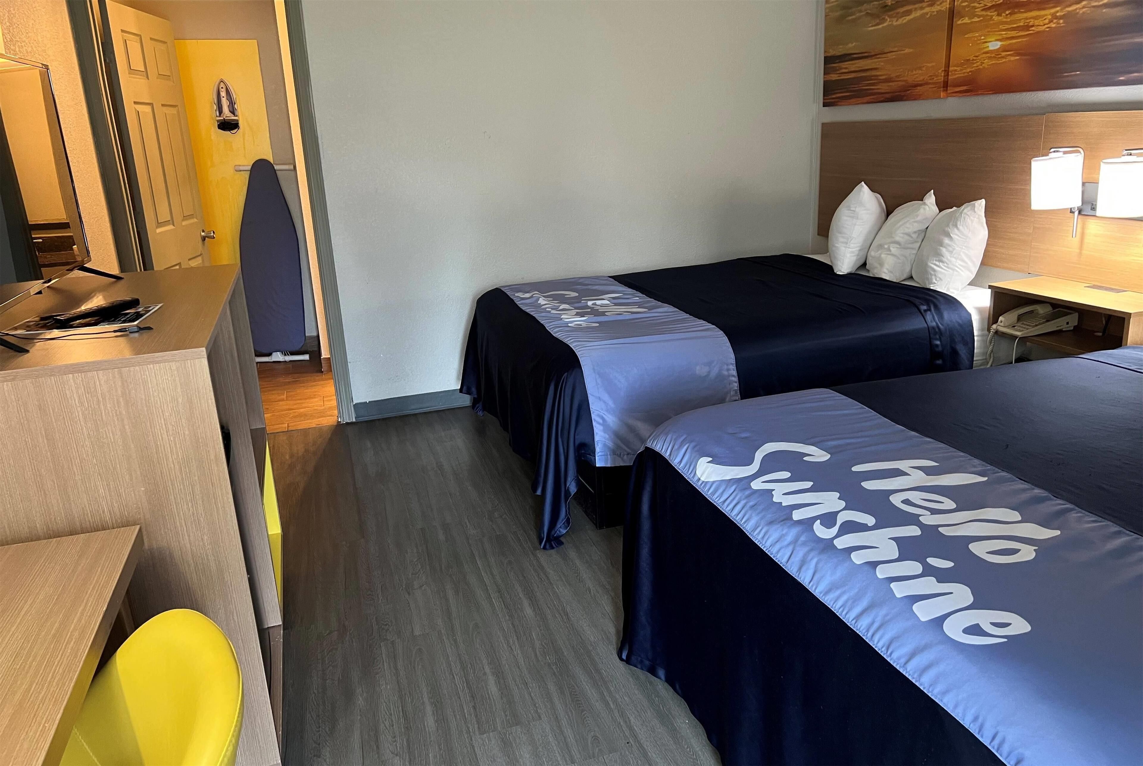 Ein Hotelzimmer mit zwei Betten, einem Schreibtisch, einem Stuhl und einer Tür.