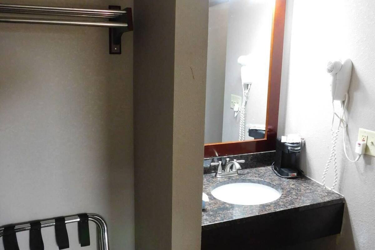 A bathroom with a sink, mirror, towel rack, and a trash bin.