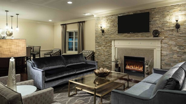 A modern living room with a fireplace, comfortable seating, and a flat-screen TV mounted on the wall.