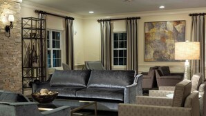 A modern living room with a dark grey sofa, patterned armchairs, a coffee table, and a decorative metal shelf.