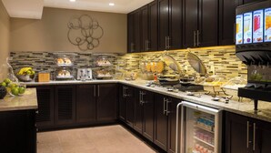 A modern kitchen with dark cabinets, a tiled backsplash, and a built-in coffee station.