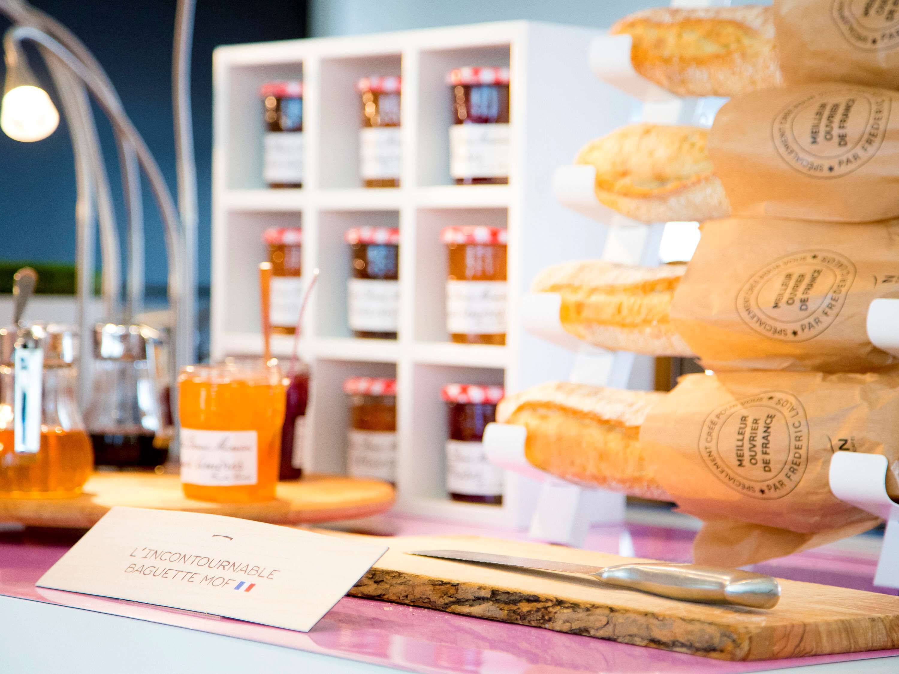 A display of baguettes and honey jars on a table with a sign reading "L'Incontournable Baguette Mois".