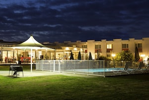Un hotel con piscina, asientos al aire libre y una zona techada.