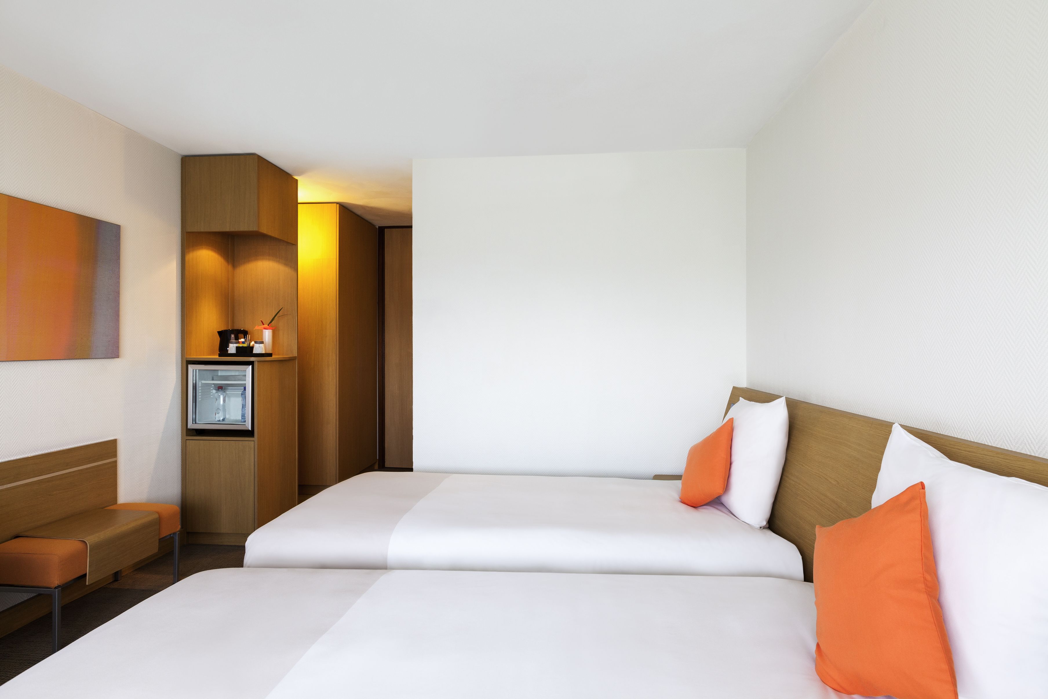 Habitación de hotel con cama doble, una zona de estar pequeña, minibar y televisión montada en la pared.