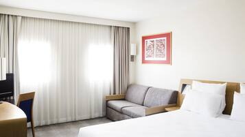 Une chambre d’hôtel avec un lit, un canapé, un bureau et une chaise.