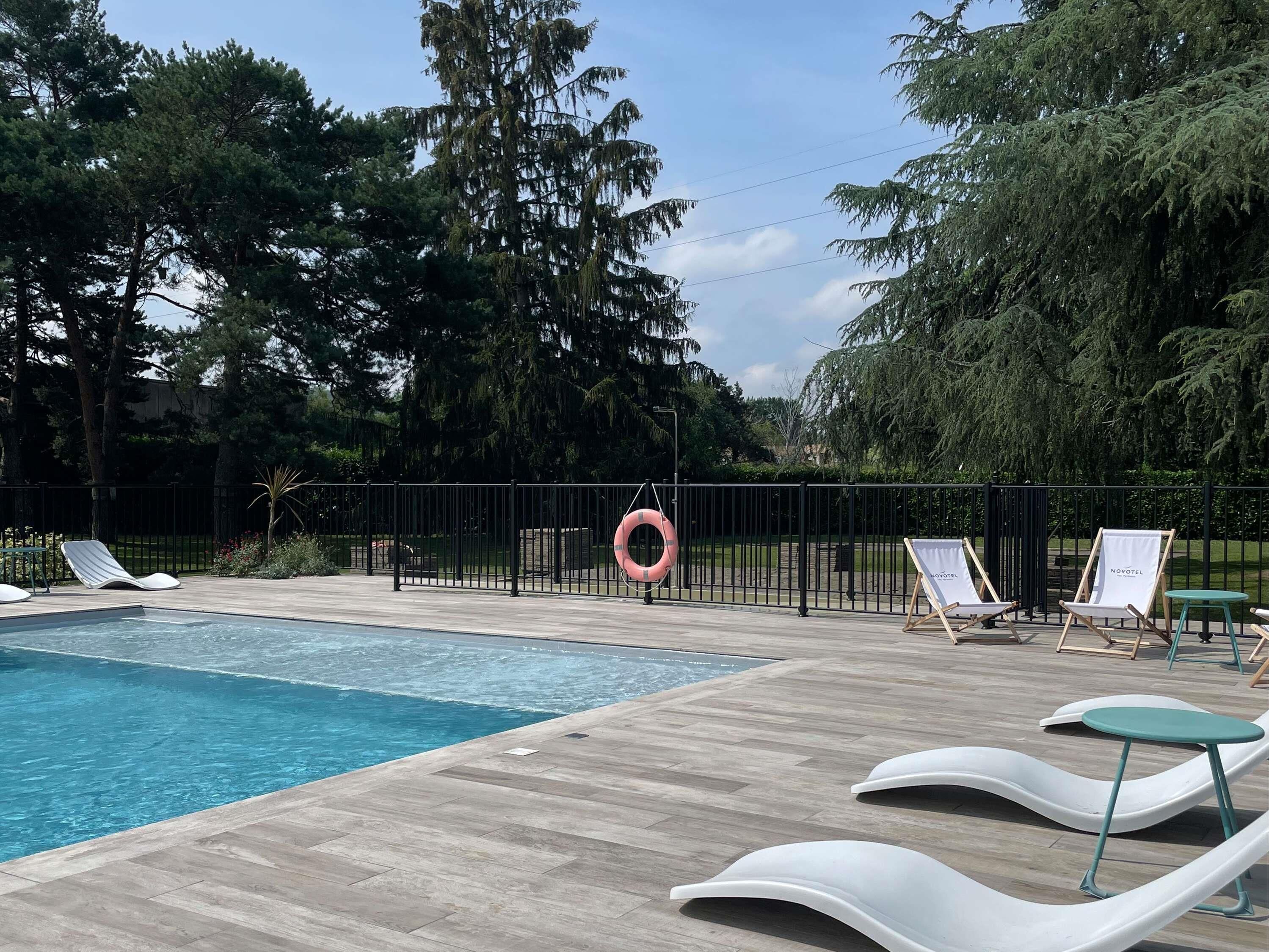 Una piscina al aire libre de temporada, sombrillas