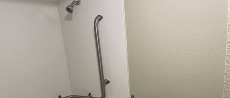 Un baño con bañera, inodoro y barras de apoyo.