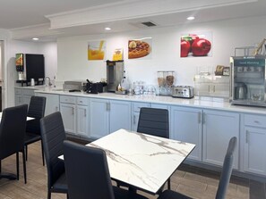 A modern kitchen with a marble countertop, black chairs, and a breakfast bar. - Quality Inn & Suites Tuscaloosa near University (Tuscaloosa)