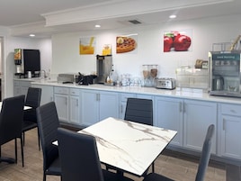 A modern kitchen with a marble countertop, black chairs, and a breakfast bar.