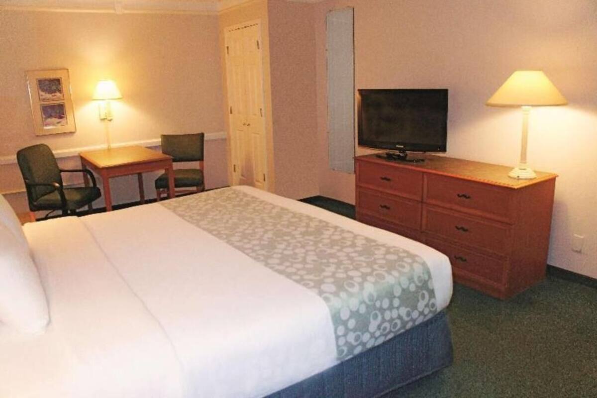 Une chambre d’hôtel équipée d’un lit, d’un bureau, d’une télévision et d’une commode.