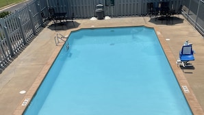 A rectangular pool with a metal ladder at the shallow end, surrounded by a wooden fence and a metal railing.