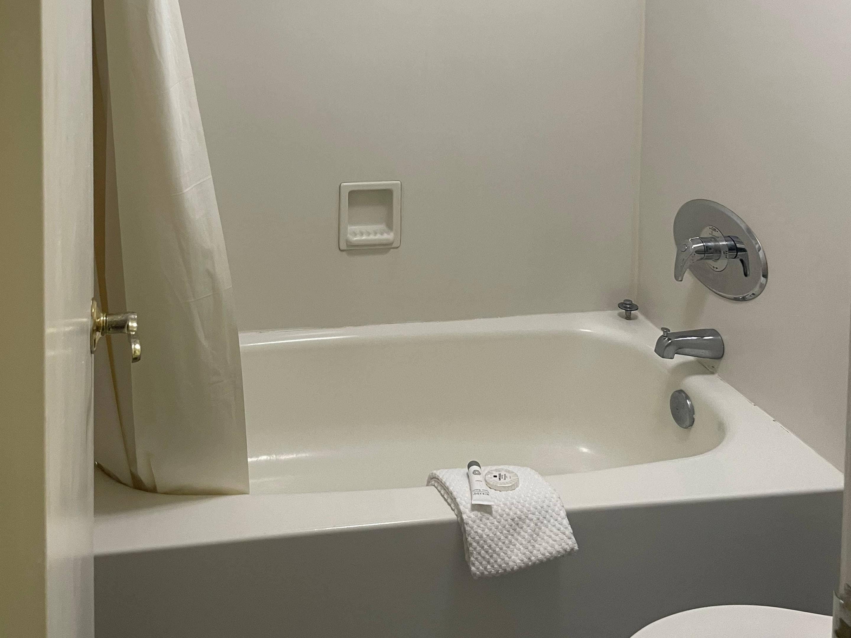 A white bathtub with a towel, a faucet, and a soap dish.