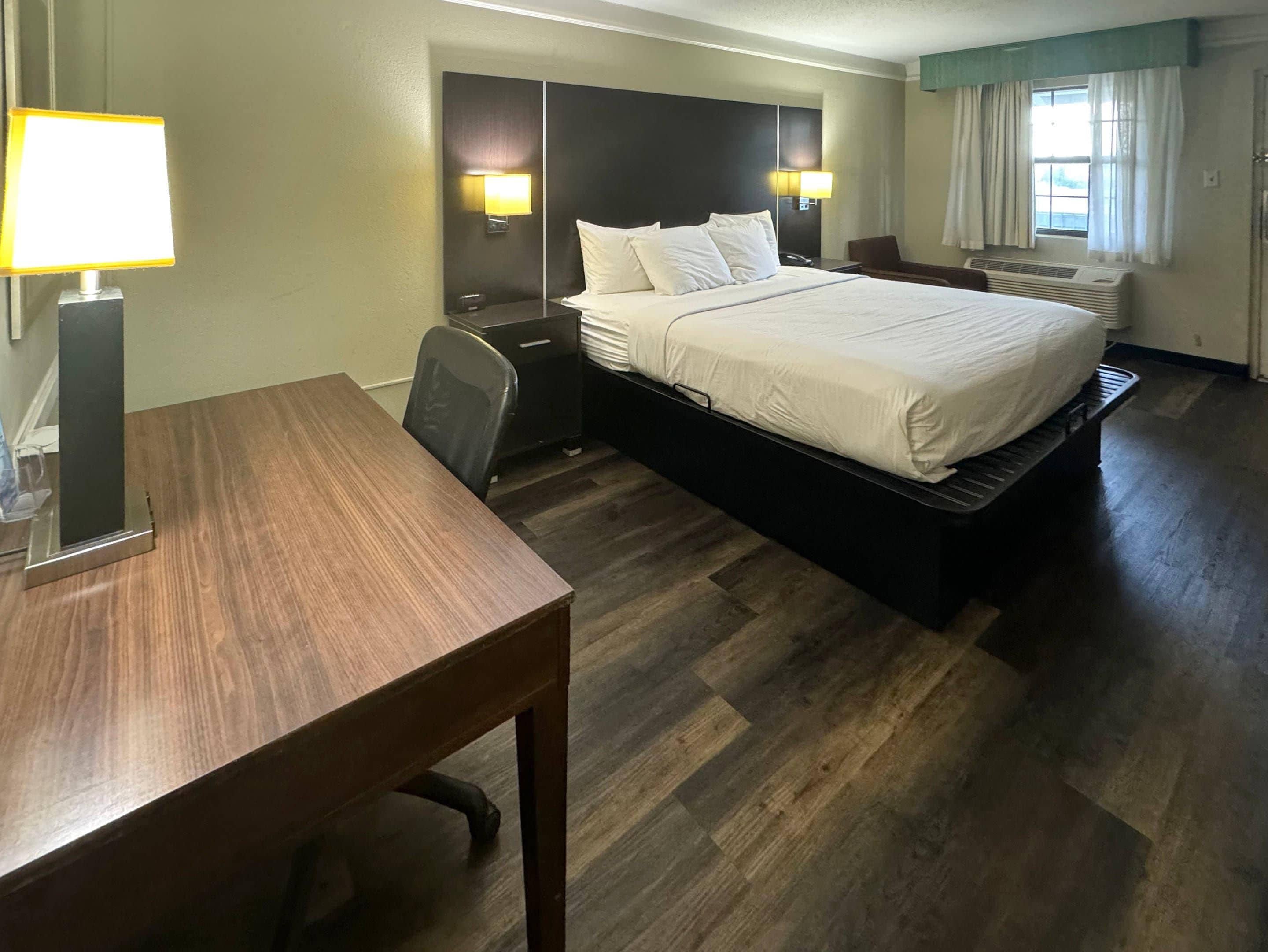 Una habitación de hotel con cama, mesitas de noche, un escritorio y una silla.