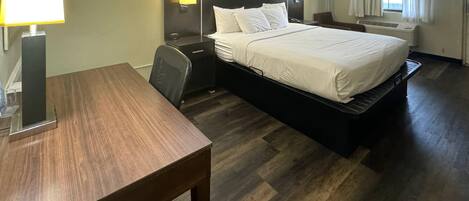 Una habitación de hotel con cama, mesitas de noche, un escritorio y una silla.