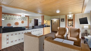 A hotel lobby with a reception desk, seating area, and a television mounted on the wall.