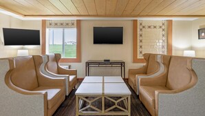 A room with a wooden ceiling, two sofas, a coffee table, a TV, and a window with a view.