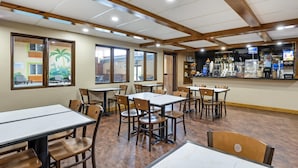 A restaurant with wooden tables and chairs, large windows, and a bar area.