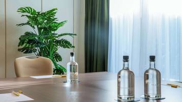 A conference table with two clear glass bottles, a potted plant, and a chair.