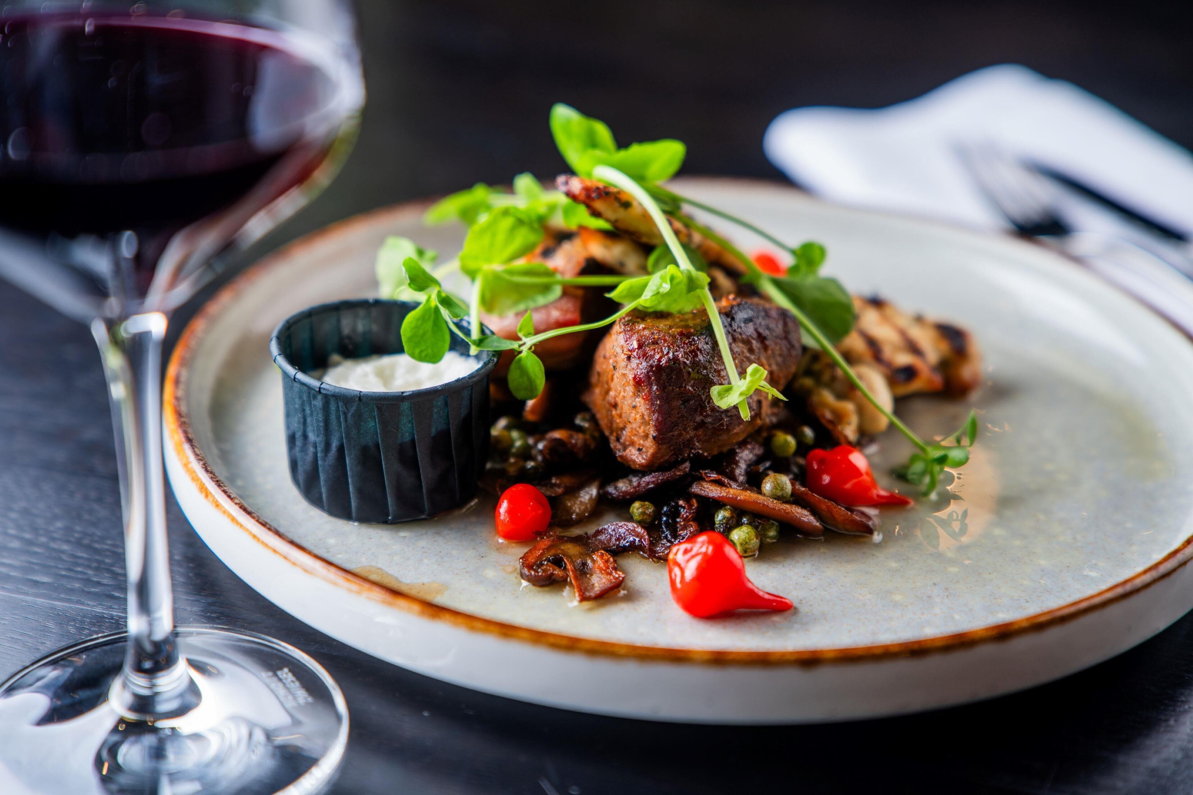 A plate of food with a glass of red wine.