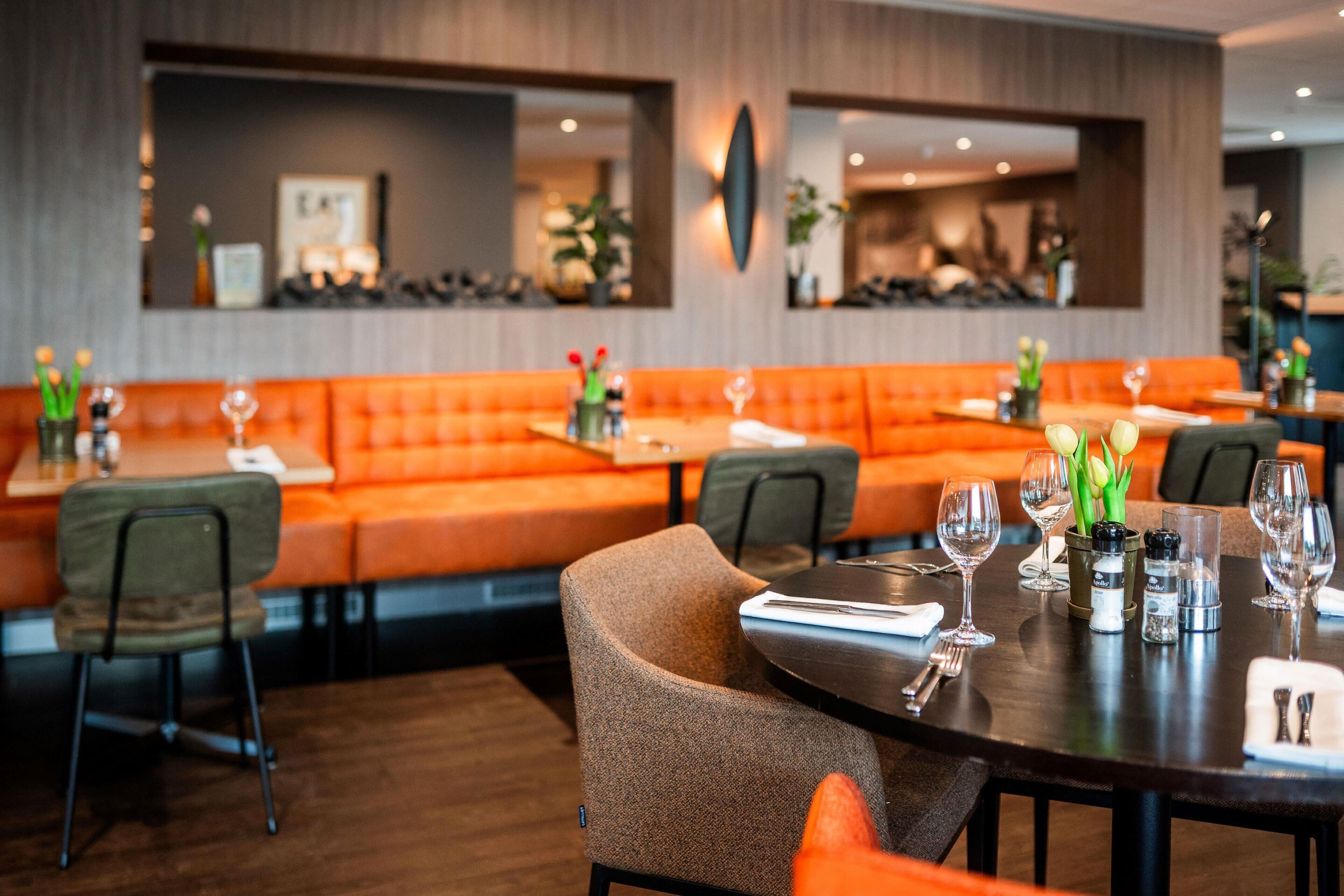 A restaurant with orange seating, a wooden floor, and a modern interior design.