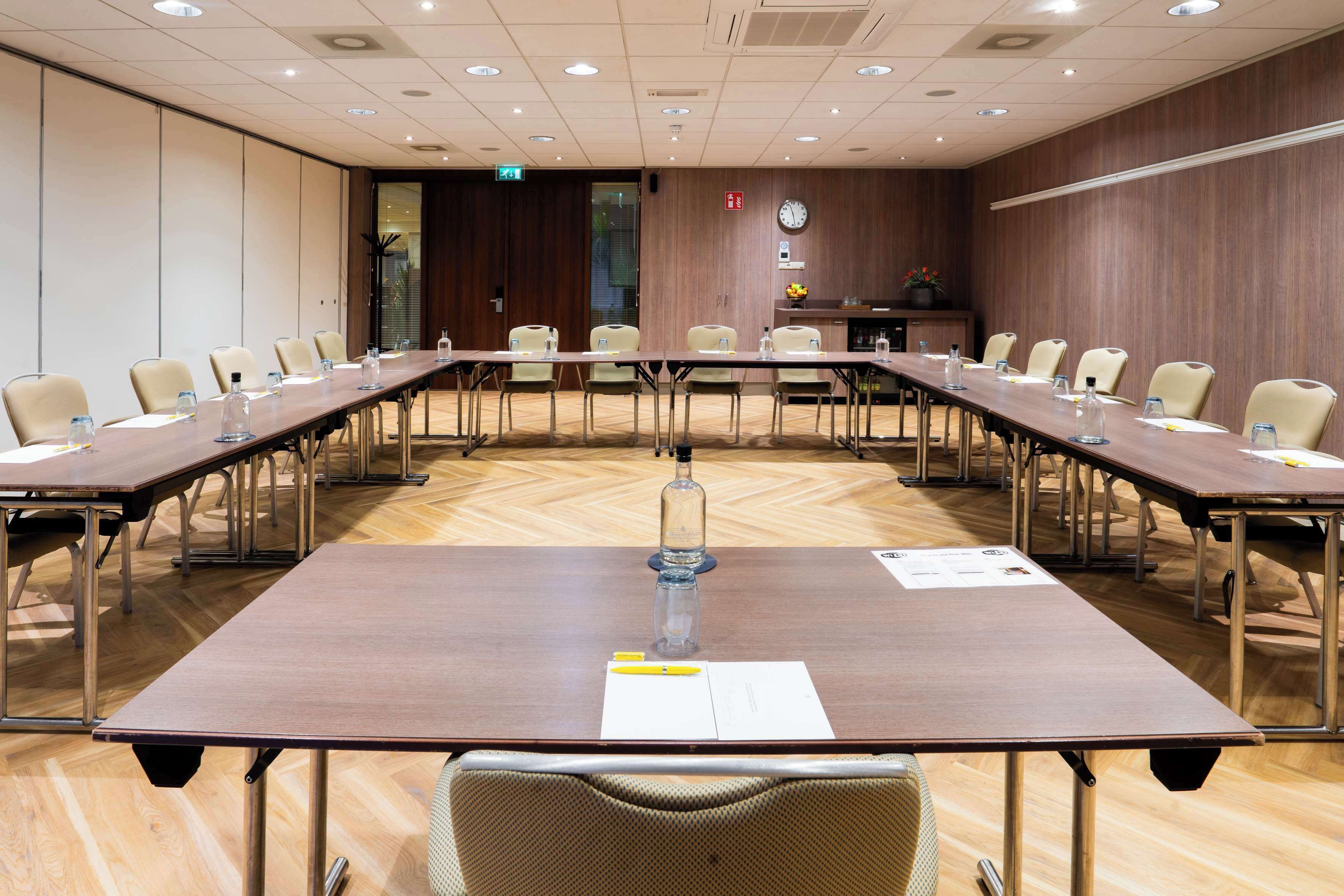 A conference room with a long table, chairs, and a clock on the wall.