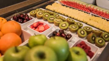 A variety of fresh fruits arranged in a display case, including apples, kiwis, cherries, and watermelon slices.