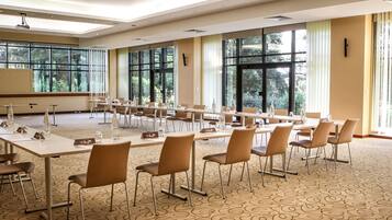 A conference room with long tables, chairs, and a carpeted floor.
