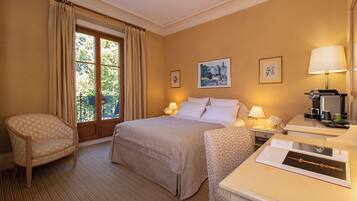 Een hotelkamer met een bed, twee nachtkastjes, een stoel en een raam met gordijnen.